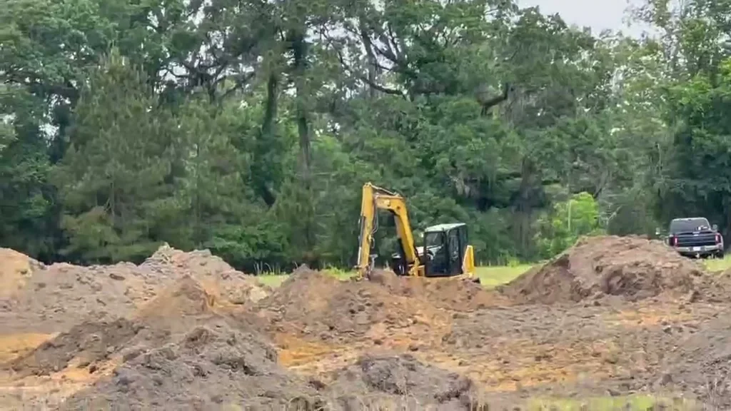 Our excavator digging on cleared land, with piles of dug soil spread across the ground in front of it