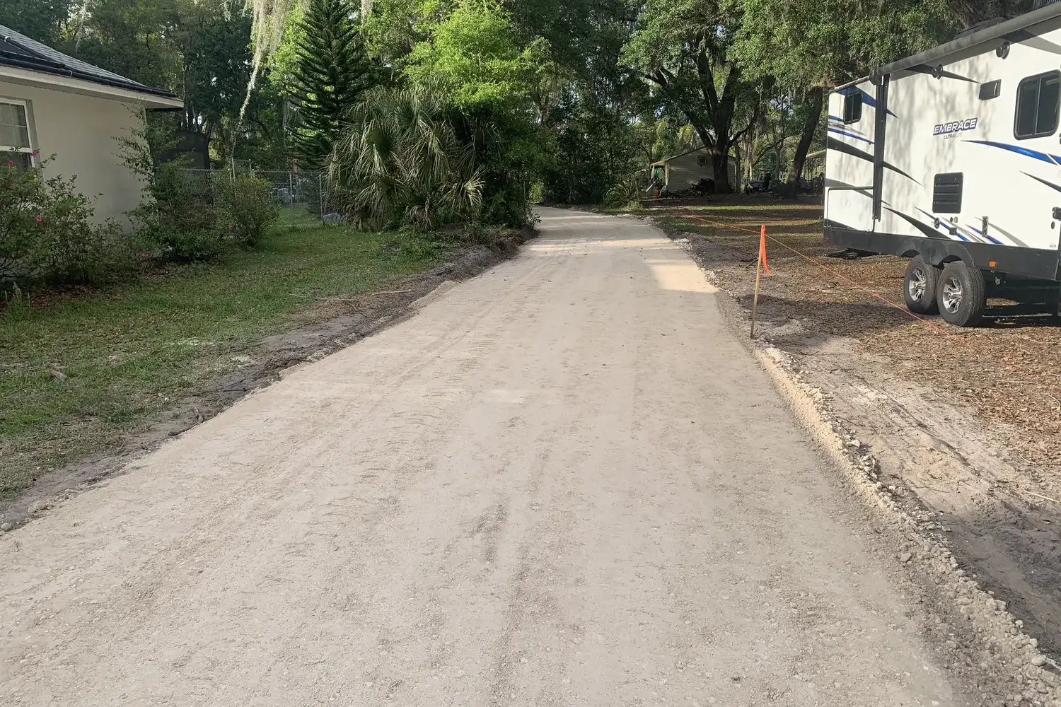 Freshly laid rock base driveway under live oaks and Spanish moss beside a house