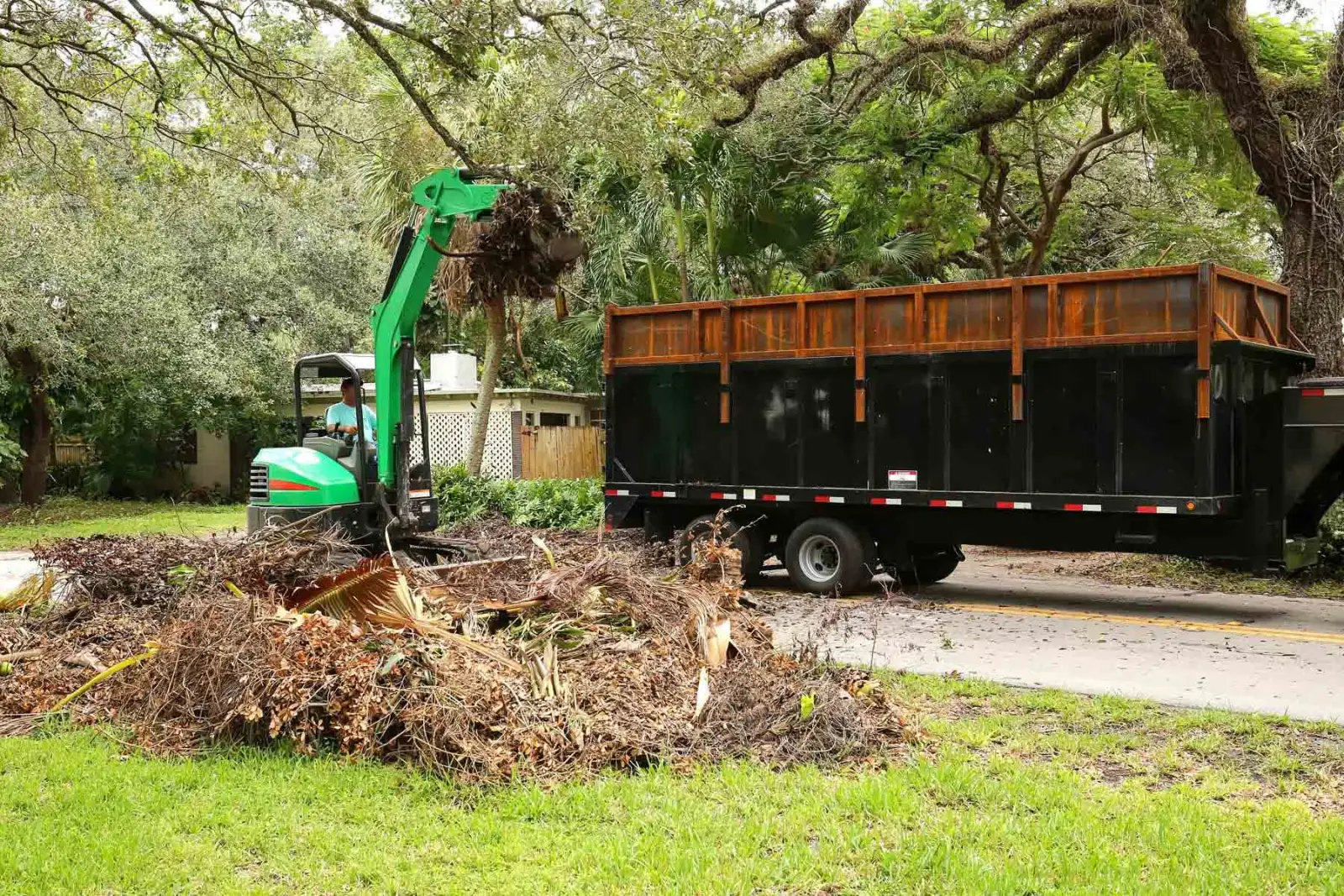 Dump truck body loaded beside a pile of brush and limbs during debris removal