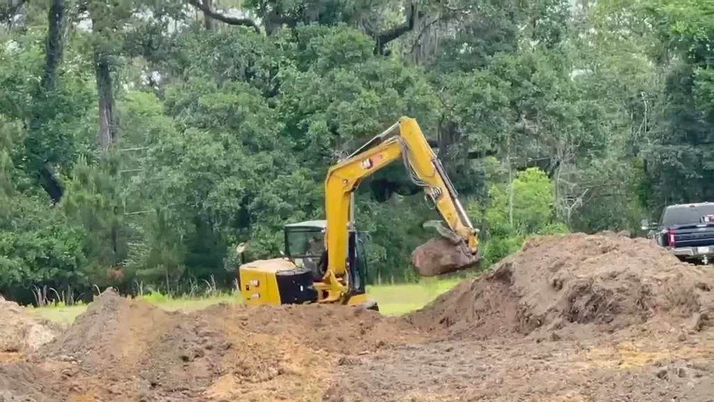 Our excavator digging on a freshly cleared lot, with piles of dug-out soil beside the hole