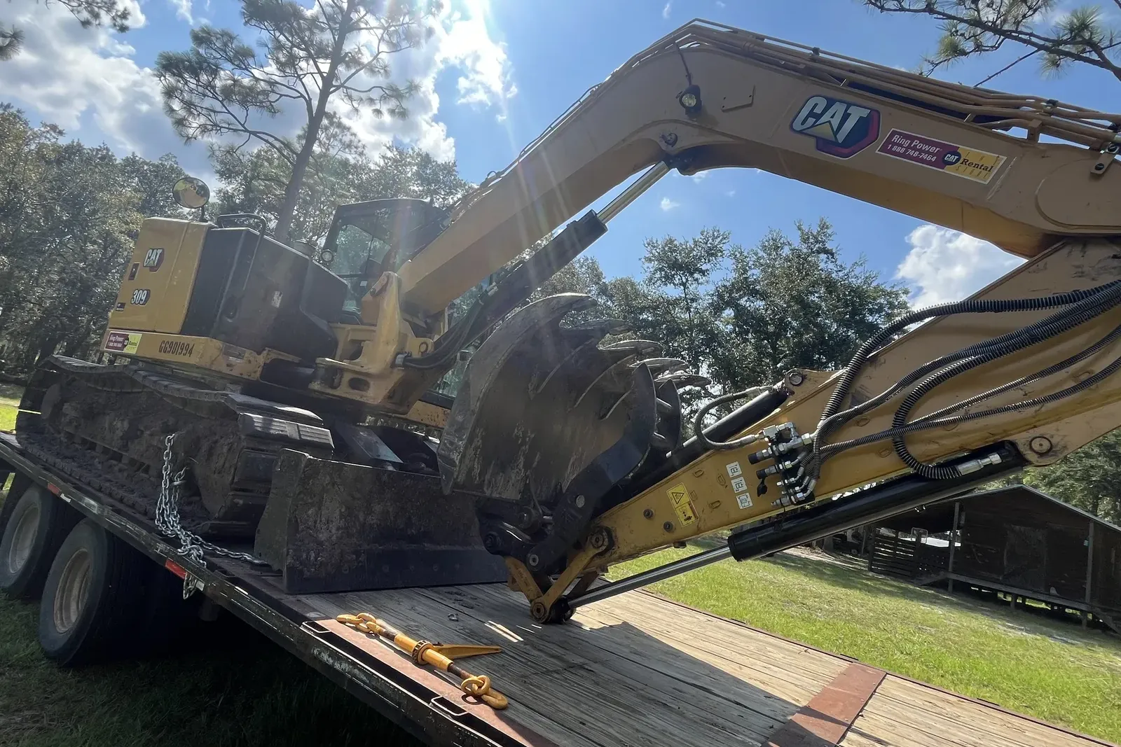 EM Land Services excavator and mulching head chained on a gooseneck trailer, the rig we haul to land clearing jobs around Havana, FL